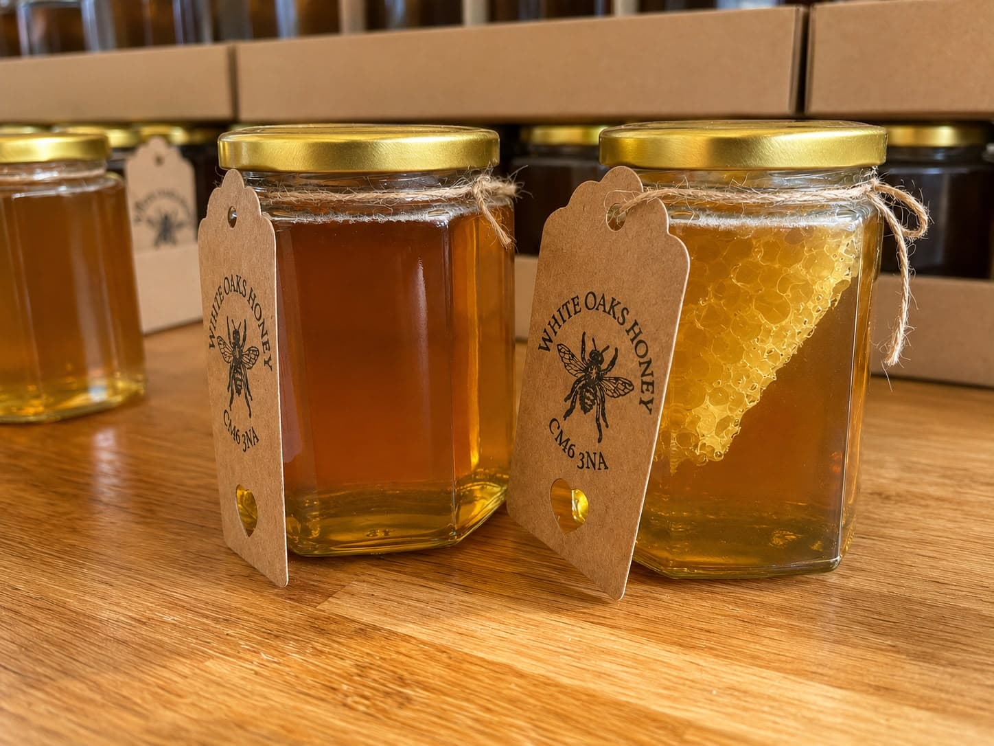 Jars of White Oaks honey with kraft tags on a wooden counter